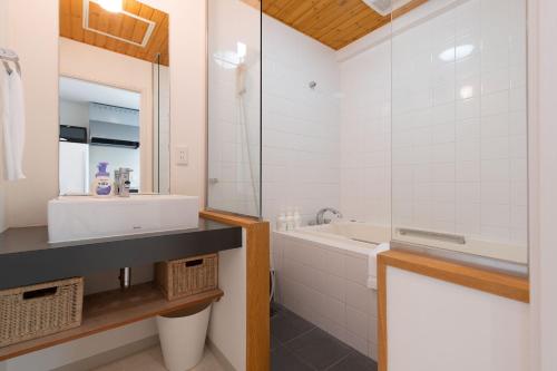 a bathroom with a sink and a tub and a mirror at Sakura Apartments in Kutchan