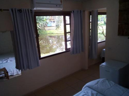 a bedroom with two windows with blue curtains and a bed at Pousada e Restaurante Dona Siroba in Morretes