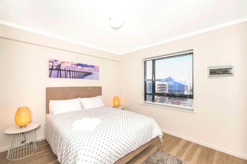 a white bedroom with a bed and a window at Perth West End Apartment 601 in Perth