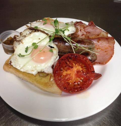 a plate of food with eggs and meat and a tomato at Bestbrook Mountain Farmstay in Maryvale