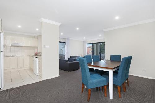 eine Küche und ein Esszimmer mit einem Tisch und blauen Stühlen in der Unterkunft Wollongong Serviced Apartments in Wollongong