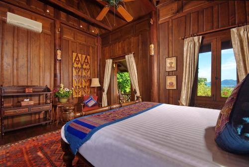 a bedroom with a bed with wooden walls and windows at Tassana Pra in Bophut 