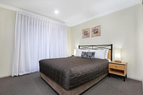 a bedroom with a large bed and a window at Wollongong Serviced Apartments in Wollongong