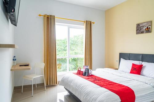 Un dormitorio con una cama grande con almohadas rojas y una ventana en RedDoorz Plus near Teras Kota 3 en Tangerang