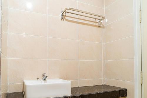a bathroom with a white sink and a tiled wall at RedDoorz Plus near Teras Kota 3 in Tangerang