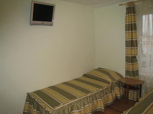 a bedroom with a bed and a tv on the wall at Aroma Skuodiškio Užeiga in Skuodas