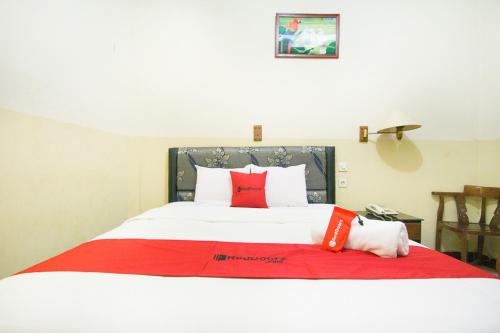 a large bed with red and white pillows on it at RedDoorz plus near Pelabuhan Bitung in Bitung