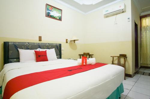 a bedroom with a large white bed with red pillows at RedDoorz plus near Pelabuhan Bitung in Bitung