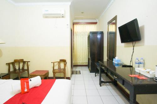 a room with a bed and a desk and a television at RedDoorz plus near Pelabuhan Bitung in Bitung