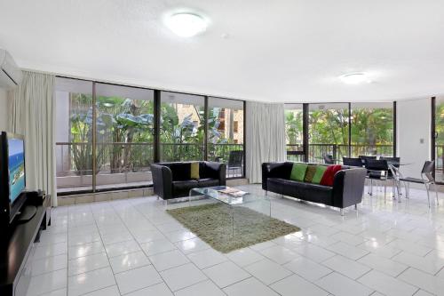 Una sala de estar con sofás, un televisor y una mesa. en Genesis Apartments by Gold Coast Premium, en Gold Coast