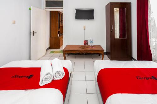 um quarto com duas camas e uma mesa em RedDoorz Syariah near RSUD Cimacan em Bogor