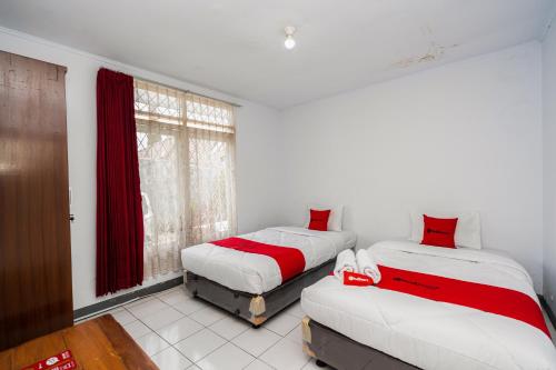 a bedroom with two beds and a window at RedDoorz Syariah near RSUD Cimacan in Bogor