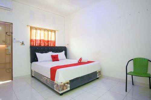 a bedroom with a bed and a green chair at RedDoorz @ Pematangsiantar 2 in Pematangsiantar