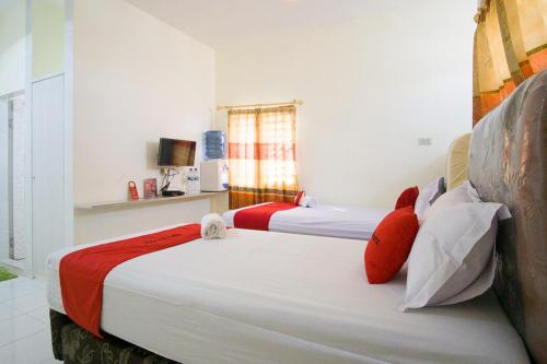 two beds with red pillows in a room at RedDoorz @ Pematangsiantar 2 in Pematangsiantar