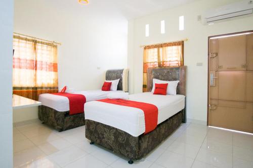 two beds in a hotel room with red and white at RedDoorz @ Pematangsiantar 2 in Pematangsiantar