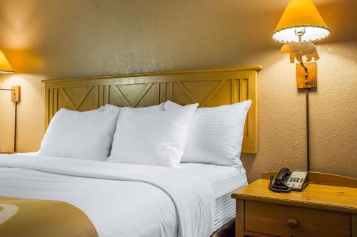 a hotel room with a bed with a phone on a table at Quality Inn Pinetop Lakeside in Pinetop-Lakeside