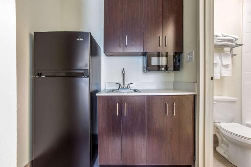 a kitchen with a black refrigerator and wooden cabinets at Days Inn and Suites by Wyndham Oxford in Oxford