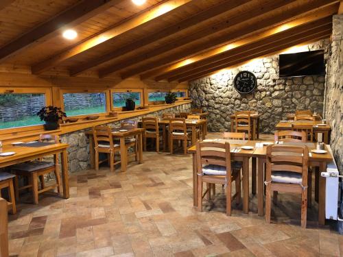 un restaurante con mesas y sillas de madera y una pared de piedra. en Plitvice Miric Inn, en Lagos de Plitvice