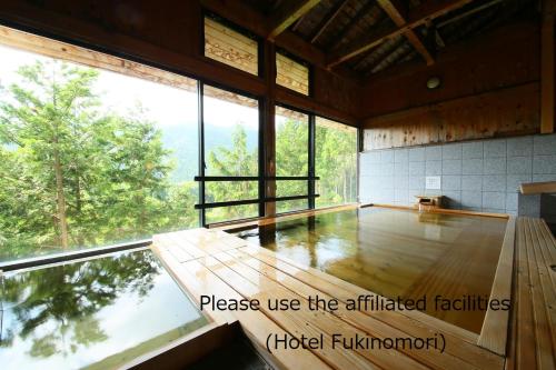 a room with a large window and a wooden floor at Tokonamiso in Nagiso