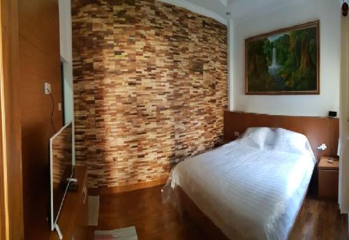 Un dormitorio con una pared de ladrillo y una cama en Pool Villa Saung Suluh, en Purwokerto
