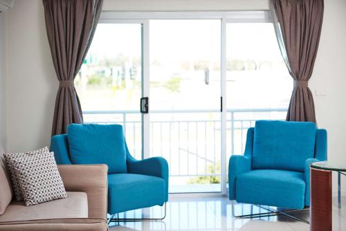 two blue chairs and a couch in a room with windows at Best Western Casula Motor Inn in Liverpool
