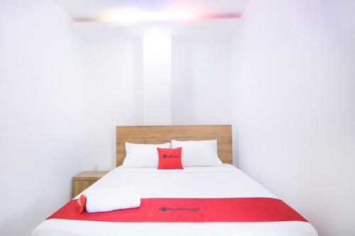 a bedroom with a white bed with a red blanket at RedDoorz @ RS Adam Malik Medan in Medan