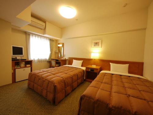a hotel room with two beds and a television at Hotel Route-Inn Shiojirikita Inter in Shiojiri