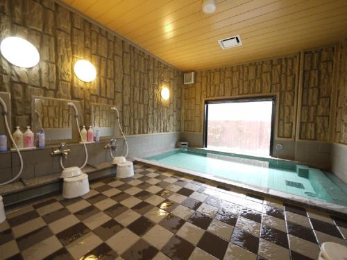 a large bathroom with a swimming pool in a room at Hotel Route-Inn Shiojirikita Inter in Shiojiri