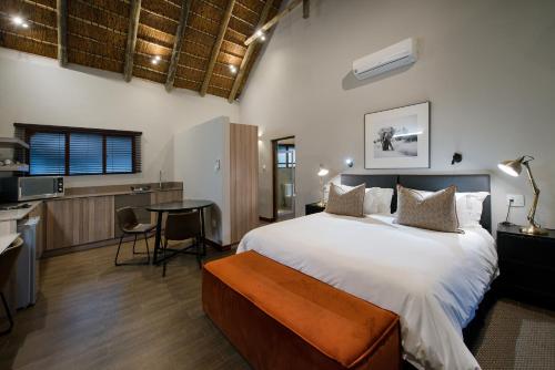 a bedroom with a large bed and a kitchen at Buckler's Africa Lodge Kruger Park in Komatipoort