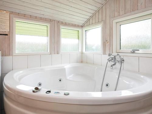 - Baño con bañera blanca y 2 ventanas en 8 person holiday home in Hj rring, en Hjørring