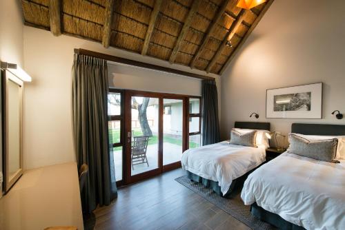 a bedroom with two beds and a patio at Buckler's Africa Lodge Kruger Park in Komatipoort