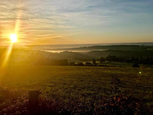 a field with the sun setting in the sky at Monsieur Doute in Durbuy