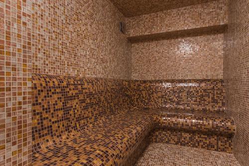 a bathroom with brown tiled walls and a bath tub at Hotel Villa Magus in Kladnitsa