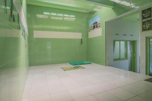 een kamer met groene muren en een witte tegelvloer bij RedDoorz Syariah near Museum Wisma Karya Subang in Subang
