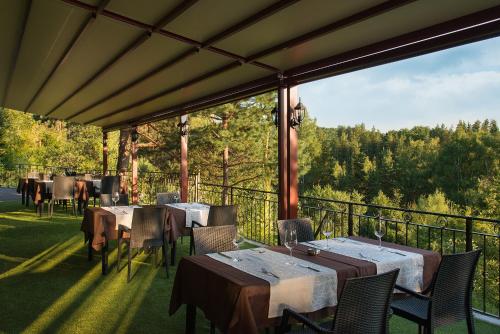 a restaurant with tables and chairs on a balcony at Hotel Villa Magus in Kladnitsa