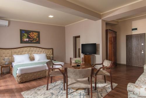 a bedroom with a bed and a table and a television at Hotel Villa Magus in Kladnitsa