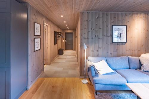 a living room with a blue couch and a hallway at Trysiltunet 16b in Trysil