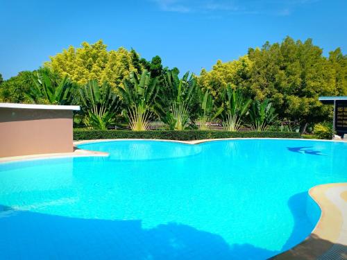 a swimming pool with blue water and trees at บ้านนกเคียงจัน ปากช่อง Nok Kiang Chan Home Pak Chong in Ban Nong Ka Cha