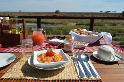 a table with a plate of food and a bowl of fruit at Buckler's Africa Lodge Kruger Park in Komatipoort