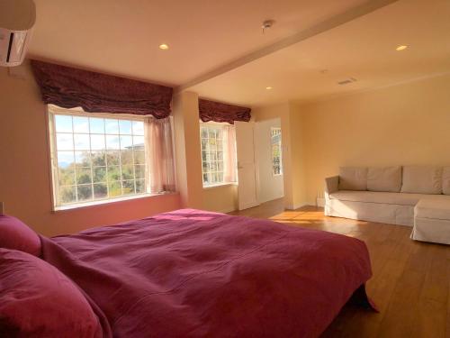 a bedroom with a bed and a couch and a window at La Krasse Angelroad in Tonosho