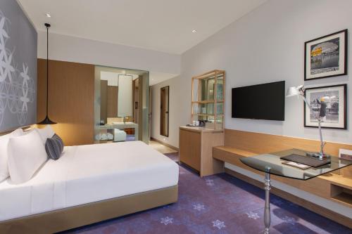 a bedroom with a bed and a desk and a television at Welcomhotel by ITC Hotels, Raja Sansi, Amritsar in Amritsar