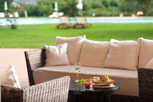 a couch and a glass of wine on a table at Hotel Aquadulci in Chia