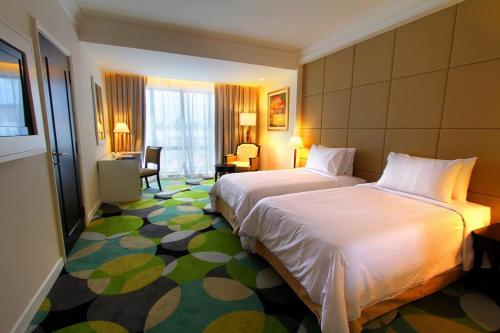 a hotel room with two beds and a desk at Perdana Kota Bharu in Kota Bharu