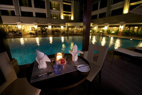 a table with a candle next to a swimming pool at Perdana Kota Bharu in Kota Bharu