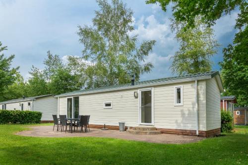 a mobile home with a table and chairs in a yard at Vakantiepark de Bergen in Wanroij