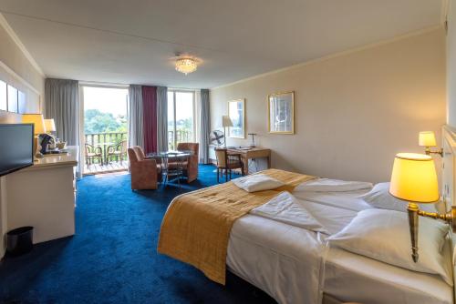 una camera d'albergo con letto, tavolo e sedie di Het Maashotel a Broekhuizen