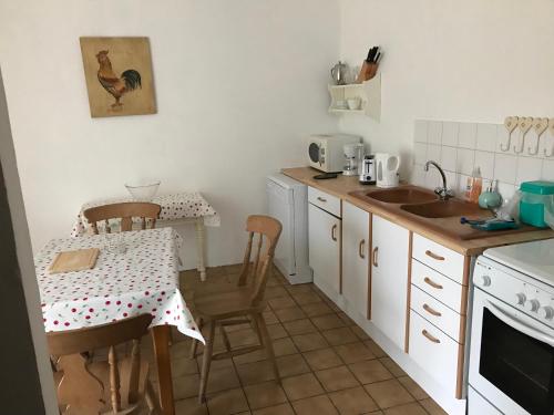 une cuisine avec une table et un évier et une table et des chaises dans l'établissement Orchid Cottage, à Gorges