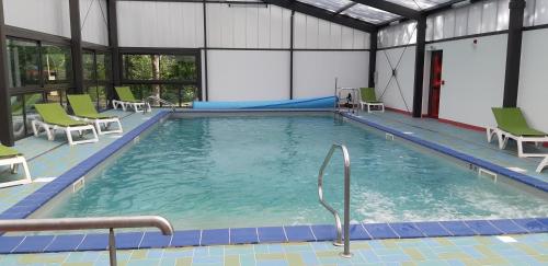 a large swimming pool with green chairs in a building at VVF Collonges-la-Rouge in Collonges la rouge