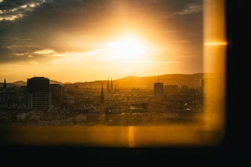 a view of the sun setting over a city at HENRI Hotel Wien Siebterbezirk in Vienna