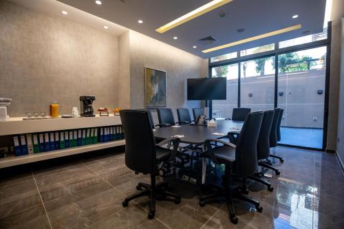 a conference room with a table and black chairs at The Compass Hotel in Amman